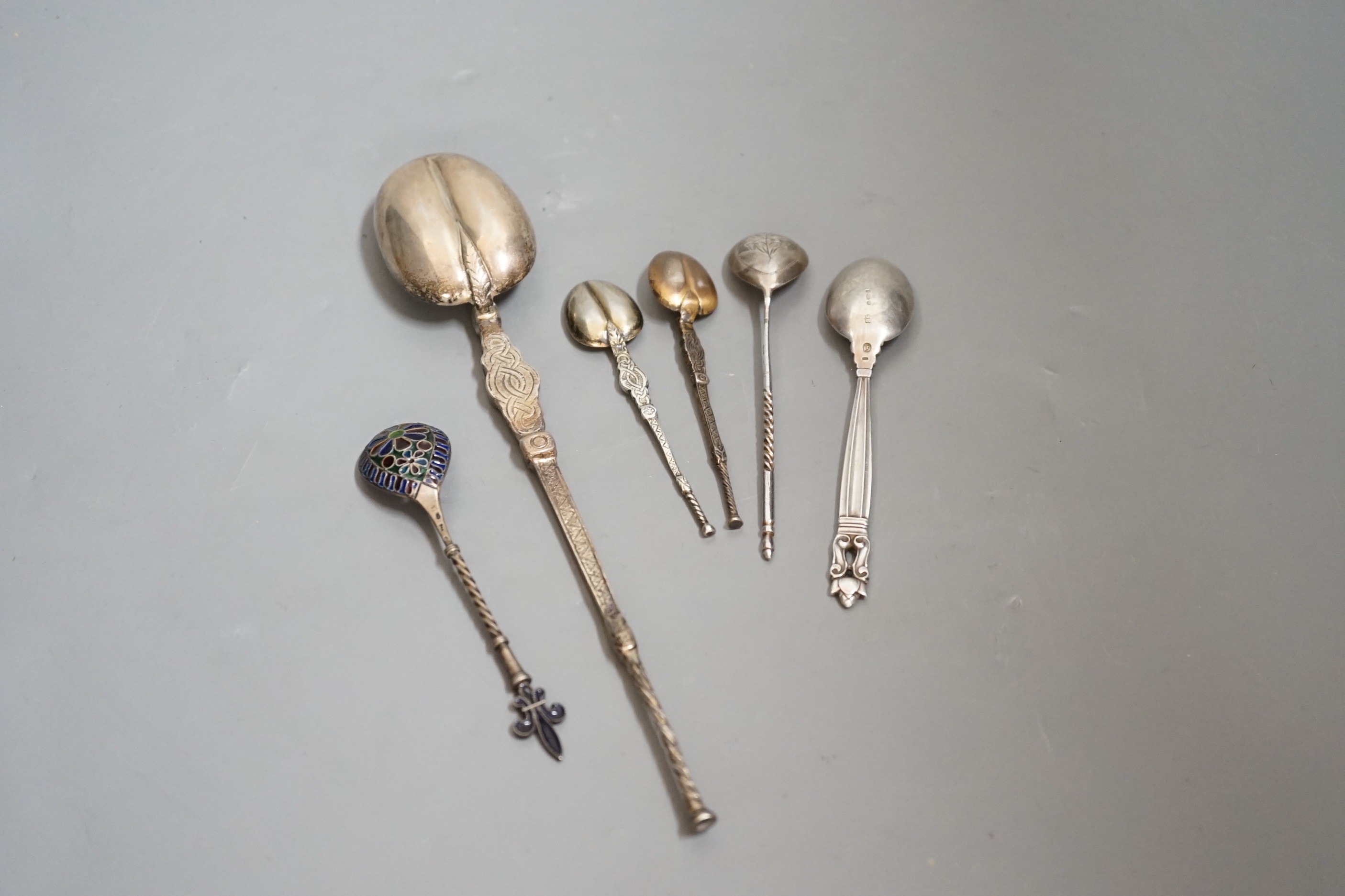 A 1930's silver replica of The Anointing spoon, 24.7cm, two similar smaller spoons, a Georg Jensen spoon, an Austro-Hungarian white metal and plique a jour spoon and a Russian tea spoon.